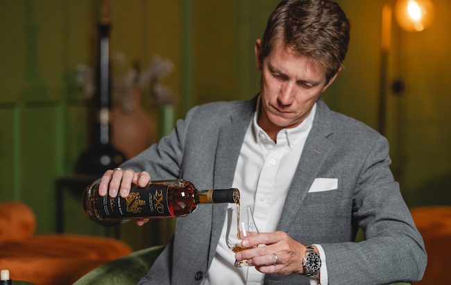 A man pours bourbon into a nosing glass