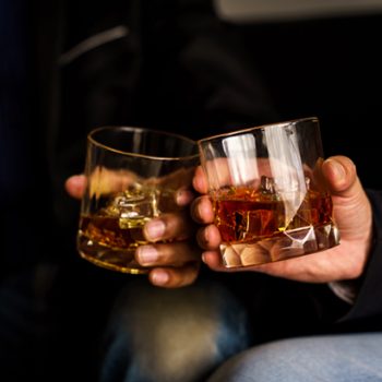 September's best stories: Two hands clink glasses of whiskey wiskey on the couch