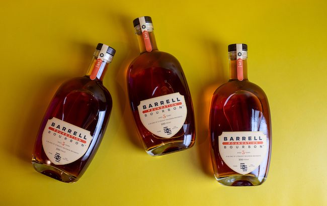 Three bottles of Barrell Bourbon on a yellow background
