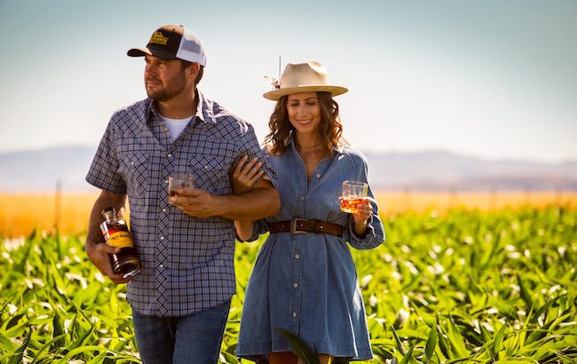 A man a woman walk through a corn field