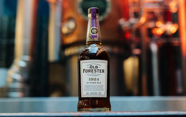 A bottle of bourbon in front of a copper still