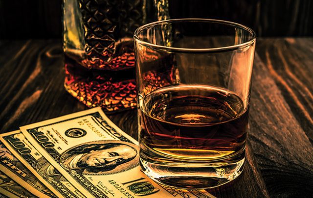 Glass of whiskey and decanter with money