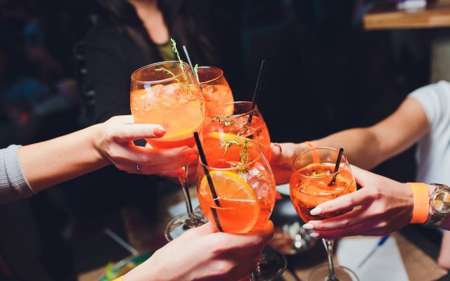 women raising a glasses of Spritz at the dinner table