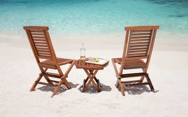 tequila shots on a teak table with two empty chairs at the Caribbean beach
