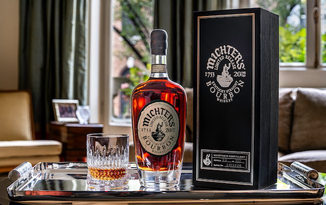 A bottle of 20 year old Michter's Bourbon and glass of whiskey on a serving tray.