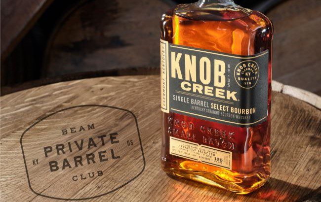 A bottle of Knob Creek Bourbon on a barrel with a graphic that reads "Beam Private Barrel Club