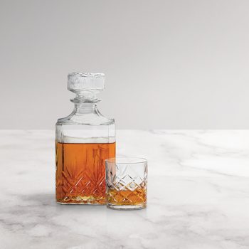 Glass and bottle of whiskey on a white marble