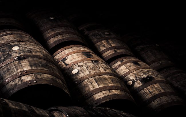 Barrels laying in the shadows. It remains to be seen how tariffs may impact barrels and other goods in the spirits supply chain.