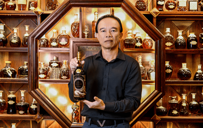 Macallan 1926 The Masterpiece Edition, held by owner Nguyễn Đình Tuấn Việt, in front of his whisky collection