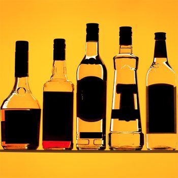 Photography of orange backlit alcohol bottles.
