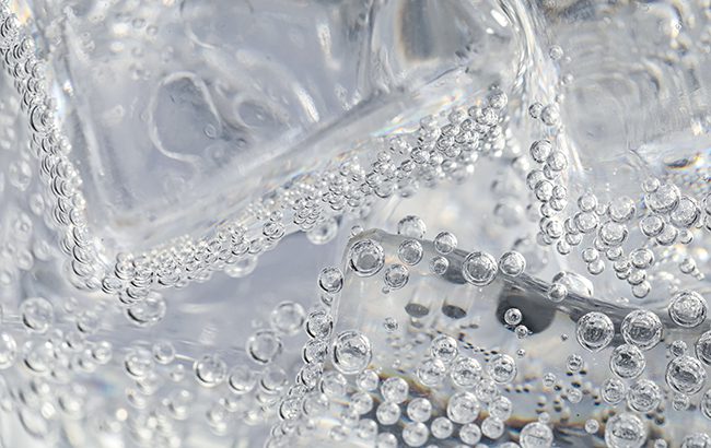 carbonation, soda water with ice as background, closeup